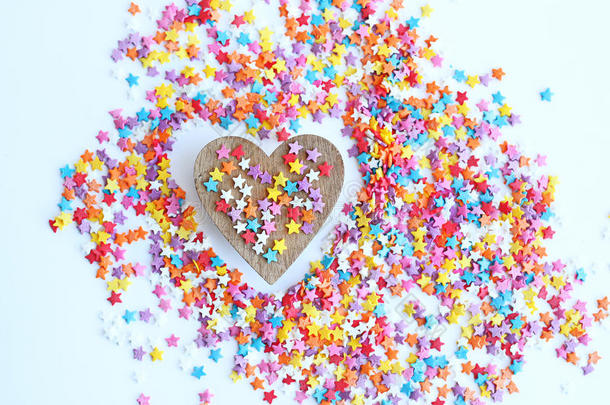 明亮的彩色糖果洒上星星和木制的心在一个轻的背景，柔和的焦点，模糊。