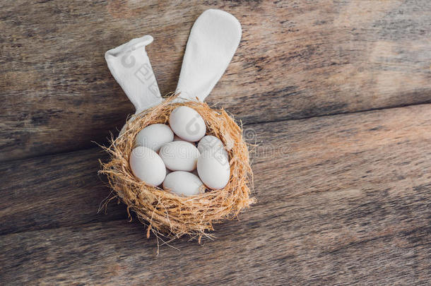 复活节那天，家里有三个白色复活节彩蛋和兔子耳朵的巢穴。 在春天庆祝复活节。 画鸡蛋