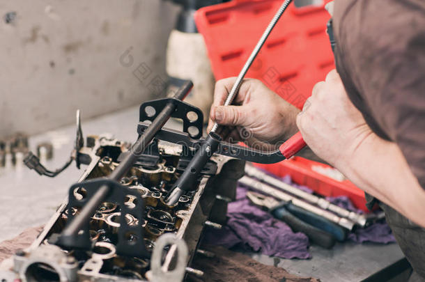 汽车修理工在车库用旧汽车发动机活塞和阀门