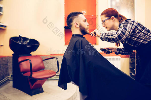 女理发师正在剪胡子男人客户的头发