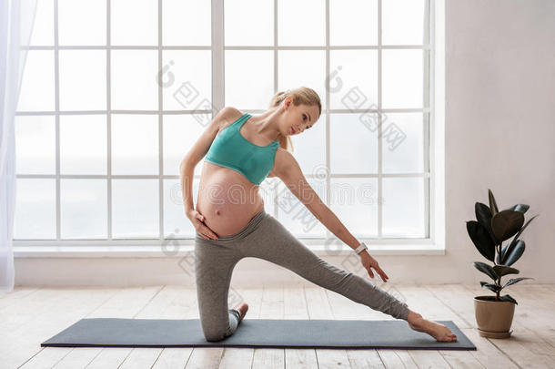 可爱的孕妇穿着运动服做瑜伽