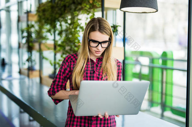 穿着智能休闲服的美丽的商业自由职业女士正在使用笔记本电脑，在现代办公室里看笔记本电脑