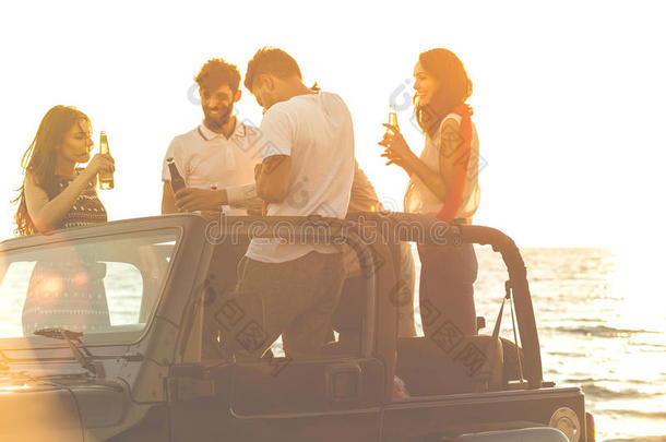 五个年轻人在日落时在海滩上开<strong>敞篷</strong>车玩得很开心。