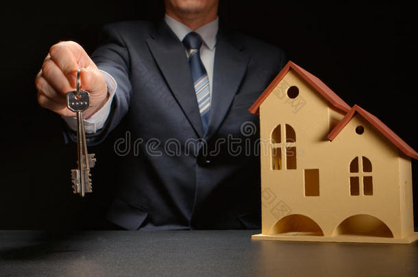 商人把钥匙放在桌子上的房子模型旁边
