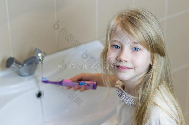 一个女孩刷牙后洗了一把电动牙刷。