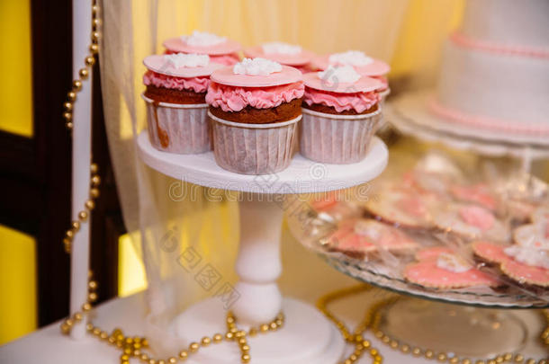放在花瓶里的桌子上的糖果棒棉花糖，粉红色的盘子，马卡龙，蛋糕和纸杯蛋糕，假期，生日，装饰