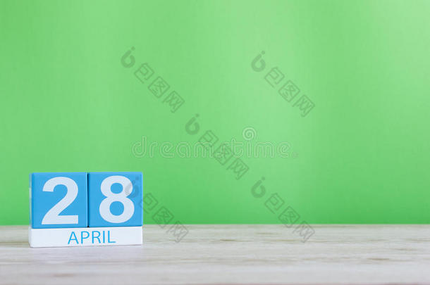 4月28日。每月28日，木制桌子和绿色背景上的日历。春天，文字空白