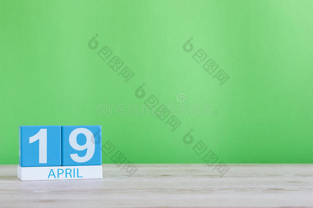 4月19日。 月19日，木桌上的日历和绿色背景。 春天的时间，文字的空空间