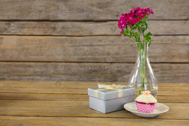 礼品盒和花瓶，盘子里有纸杯蛋糕，放在木板上