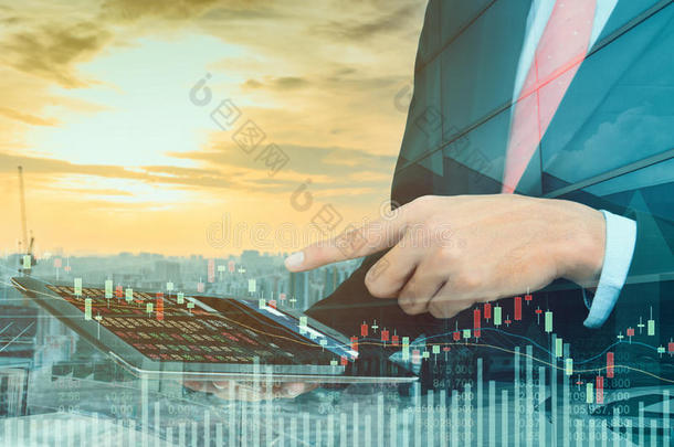 商人交易概念使用平板电脑与金融图形在城市景观背景下，双重曝光风格