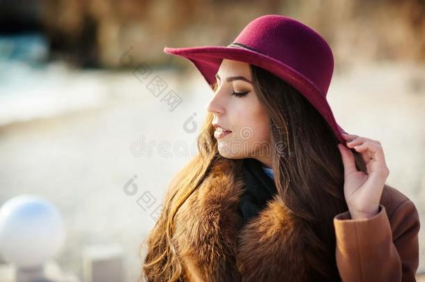 戴着帽子和涂着红色口红的外套的漂亮女孩闭上眼睛，在公园里放松