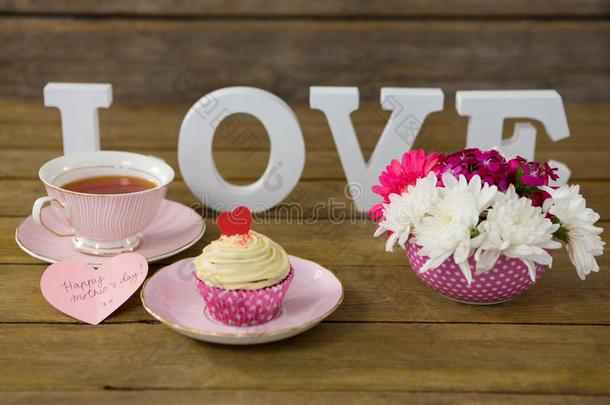 纸杯蛋糕，茶，花瓶和快乐母亲日问候卡在托盘