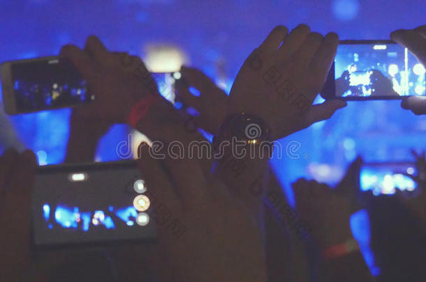 歌迷们在音乐会上用智能手机录制视频和拍照。 人们聚集在摇滚音乐会上聚会