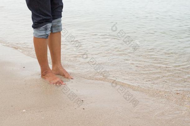 赤脚腿在海边散步，在夏天的海上度假