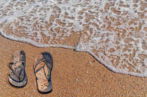 沙滩上的黑色拖鞋