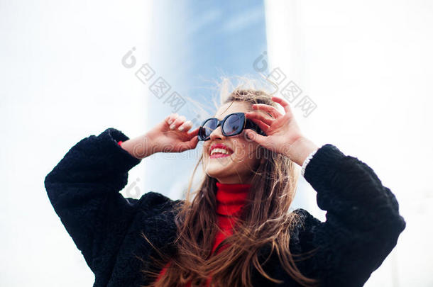 时尚肖像年轻优雅自信的女人户外。 黑色夹克，红色嘴唇和太阳镜。