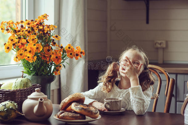 秋天的早晨在家吃早餐的小女孩。乡村住宅的真实生活舒适现代室内设计