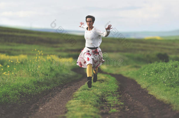 自由概念。 欢快的女孩在乡间路上奔跑