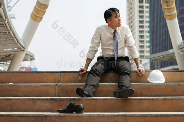 一个人坐在楼梯上疲劳或压力大的商人