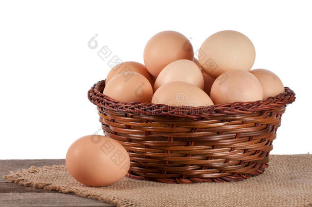 在白色背景上的柳条篮子里的木桌上的鸡蛋
