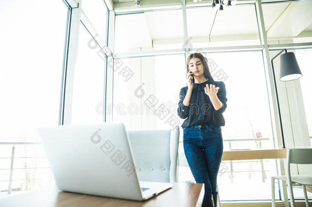 <strong>商务</strong>女士穿着便装，在桌子附近用笔记本电脑<strong>打电话</strong>