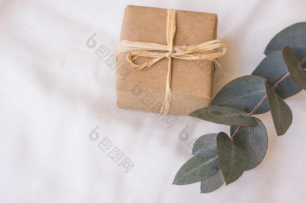 礼品盒包在工艺纸上，用缠绕，银元桉树的树枝绑在白色亚麻织物上