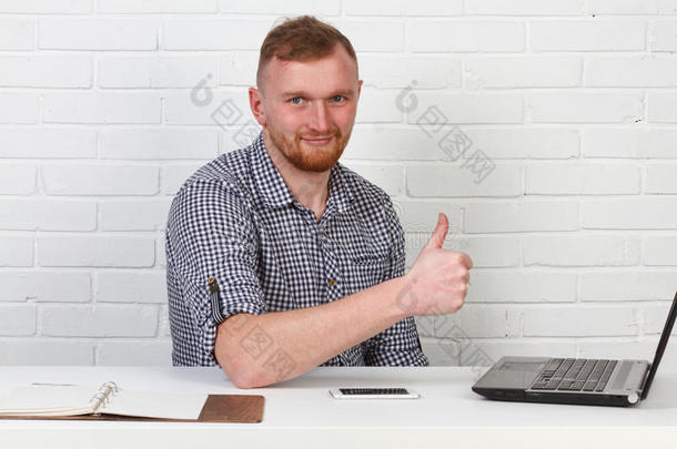 商人坐在桌子旁，在电脑上工作。 它解决了重要的业务任务。 他很成功，也很有修养