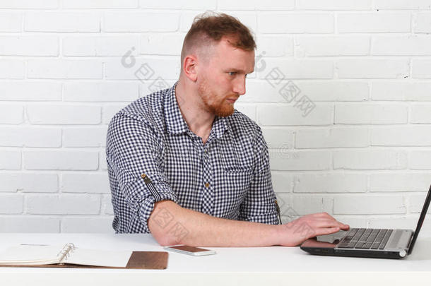 商人坐在桌子旁，在电脑上工作。 它解决了重要的业务任务。 他很成功，也很有修养