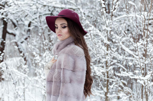 美丽可爱优雅的女孩穿着毛皮<strong>大衣</strong>和帽子，在<strong>冬天</strong>的森林里散步，明亮的霜冻的早晨