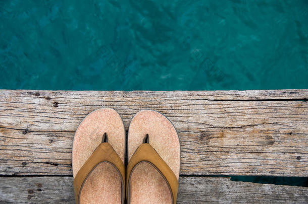 米色拖鞋凉鞋在木坞边缘的水