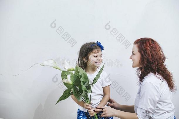 美丽的小女孩在白天给年轻的母亲送花