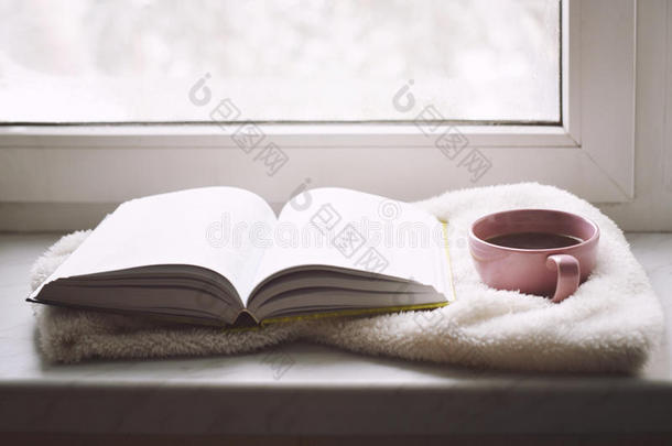 舒适的家庭静物：一杯热咖啡和打开的书与温暖的格子在窗台上<strong>抵御</strong>雪。 免费复制空间