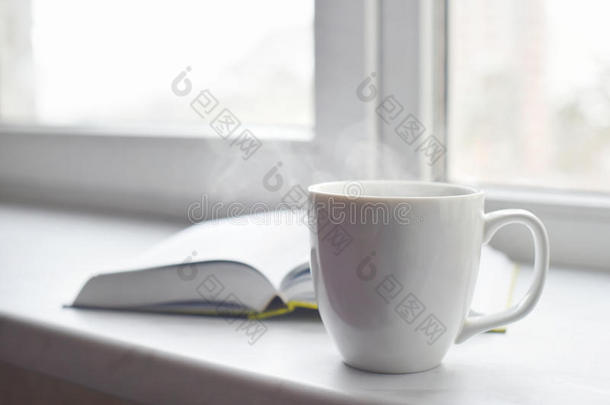 舒适的家庭静物：一杯热咖啡或茶，打开窗台上的书。 教育理念，免费复制空间