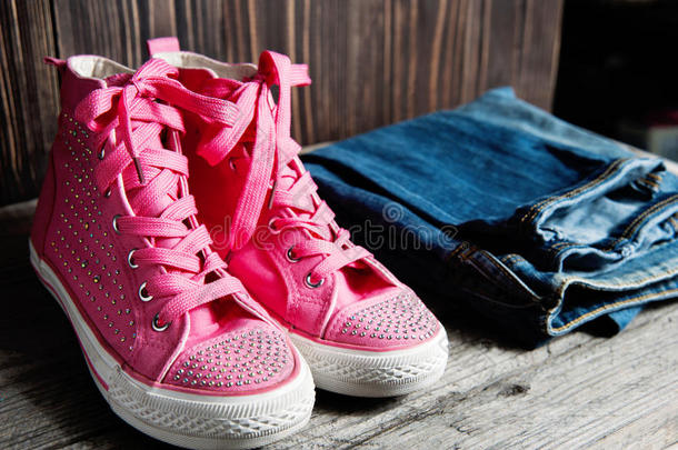 一双粉红色闪亮的鞋子和蓝色牛仔裤，适合木制背景的女孩