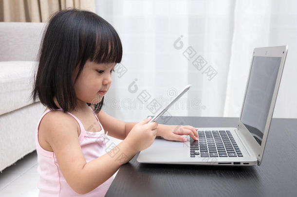亚洲中国小女孩忙着阅读手机和笔记本电脑
