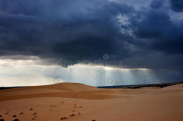 黑暗的黑色风暴云与穿透阳光覆盖沙漠景观。