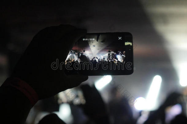 球迷双手录制视频与智能手机在摇滚音乐会和美丽的Bokeh