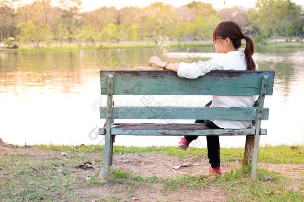独自一人，年轻的女人坐在长凳上，看着我的某个地方