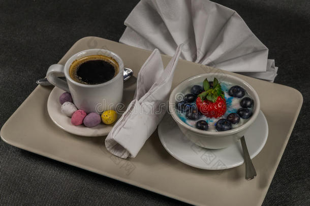 黑<strong>咖啡</strong>在奶油杯，甜点，酸奶与大草莓和<strong>蓝莓</strong>，在灰色盘子，餐巾纸，甜鸡蛋
