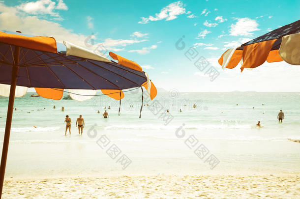 热带海滩上的雨伞，夏天人们在海滩上放松。