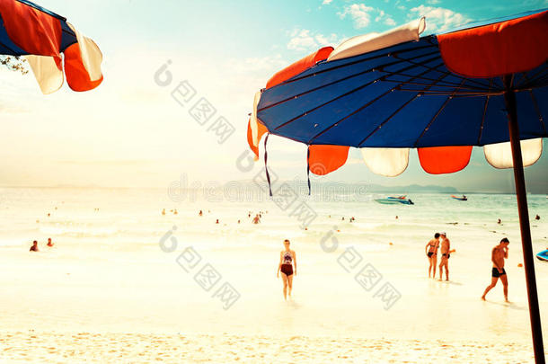 在热带海滩上的一把伞，在夏天，模糊的人在海滩上放松