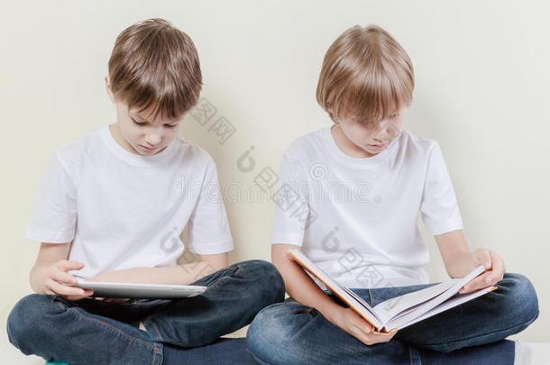 有平板电脑的男孩和在读书的孩子。 儿童教育休闲理念。