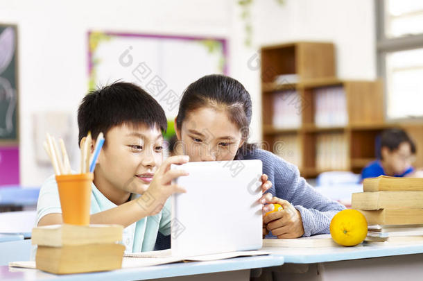 亚洲小学生和小学生一起使用平板电脑