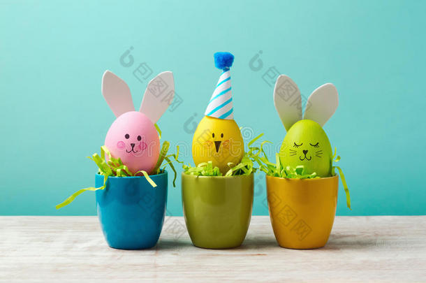 复活节假期概念与可爱的手工鸡蛋，兔子，小鸡和派对帽子在杯子里