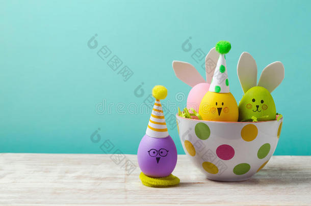 复活节假期概念与可爱的手工鸡蛋，兔子，小鸡和派对帽子在碗里