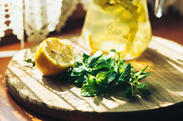 新鲜柠檬水在罐子与黄色柠檬和薄荷在木制厨房背景。 水排毒。