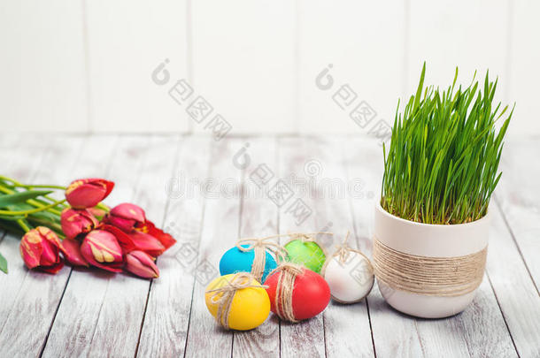 彩色复活节彩蛋，<strong>花盆</strong>与绿色的草和美丽的郁金香在木制背景。