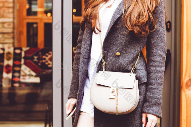 时尚和美丽。 一个手提包和一件灰色一件灰色外套。 特写，街头风格。