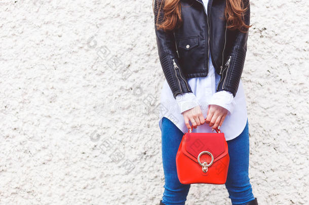 时尚和美丽。 这位时髦的女孩手里拿着一个时髦的红色小手提包。 特写，街头风格