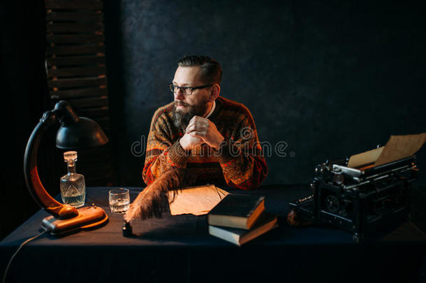 戴眼镜的胡子作家坐在桌子旁